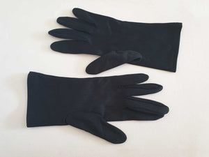 Smart black gloves for a classic dressed up look. Below wrist length stretch gloves have a striped pattern in the weave with a tiny transparent line, giving the look of a line of fine scoring. Mid weight. Fabric is nylon. No brand tag - 1960s. Large.