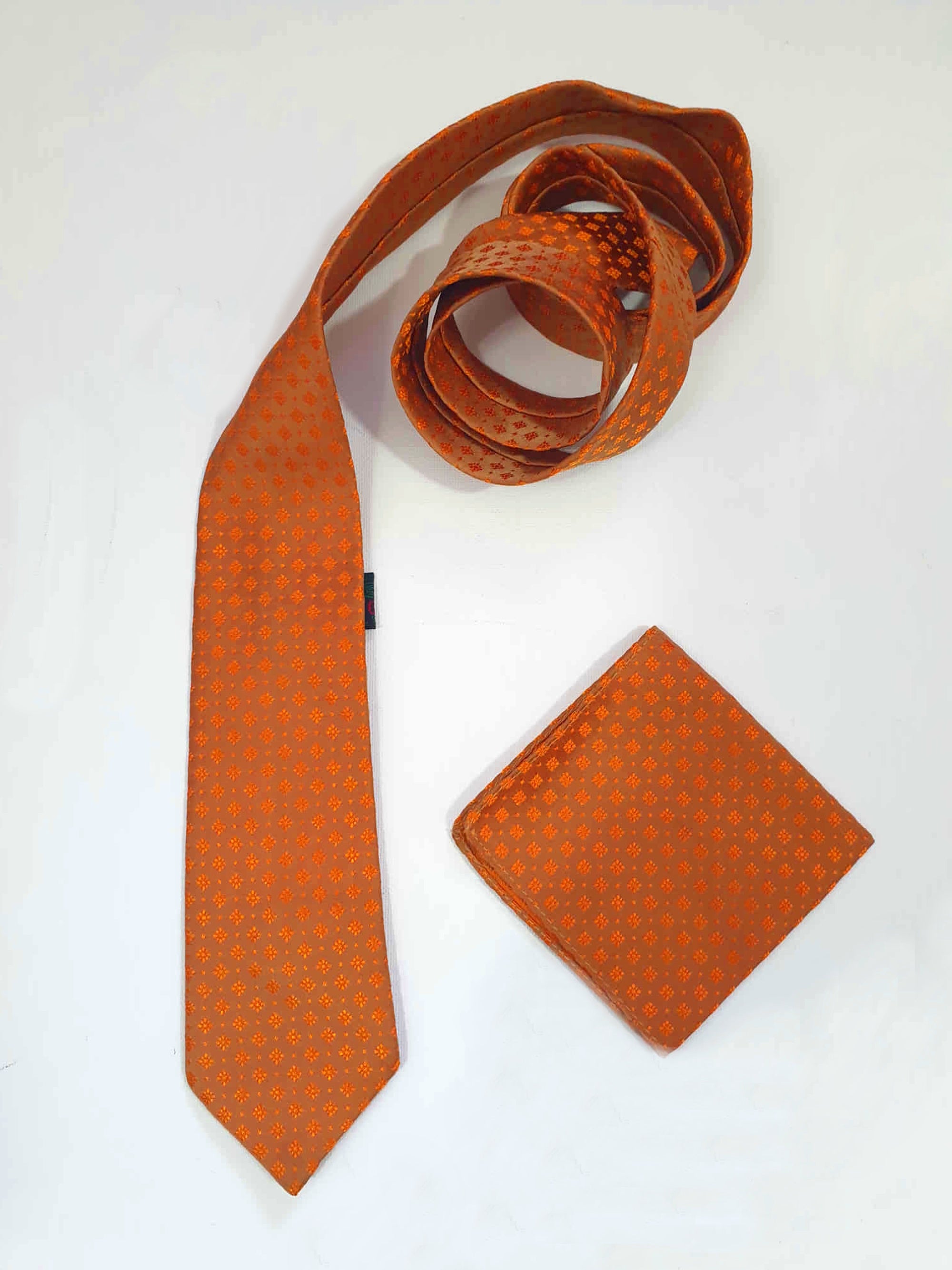 Burnt orange tie and pocket square set for a pop of colour. 
Brocade set - The fabric is woven to show a matt background and shiny medallion designs. 100% polyester. Brand is Vogue of Sydney - 1960s.