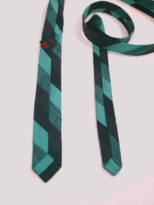 Super skinny tie in shades of grey-blue, grey and black. The grey band has a black fleck. Fabric is 100% polyester. Label reads "Superloom by Rodney" - 1960s. Blade width 3.7 cm (1.5") Length 130 cm (51") Excellent condition.