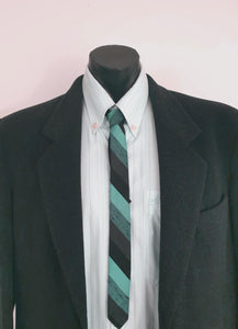 Super skinny tie in shades of grey-blue, grey and black. The grey band has a black fleck. Fabric is 100% polyester. Label reads "Superloom by Rodney" - 1960s. Blade width 3.7 cm (1.5") Length 130 cm (51") Excellent condition.