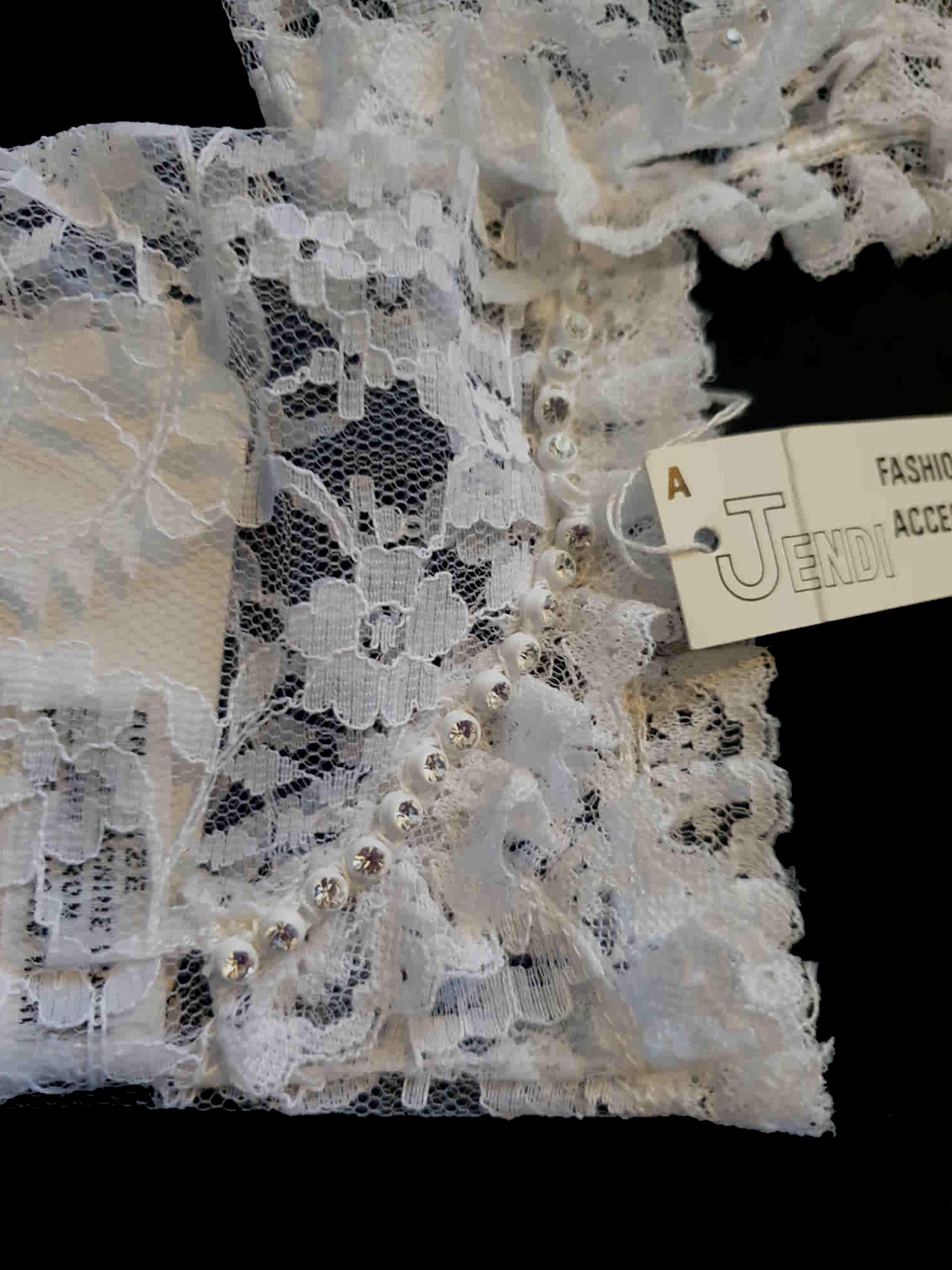 New old stock - beautiful lace bridal gloves with diamante trim, unsold stock from a former 1980s bridal boutique. White lace gloves are below-wrist length and have a shaped opening trimmed with more lace and a line of diamantes. 100% nylon. Made in Hong Kong for Jendi - 1980s.