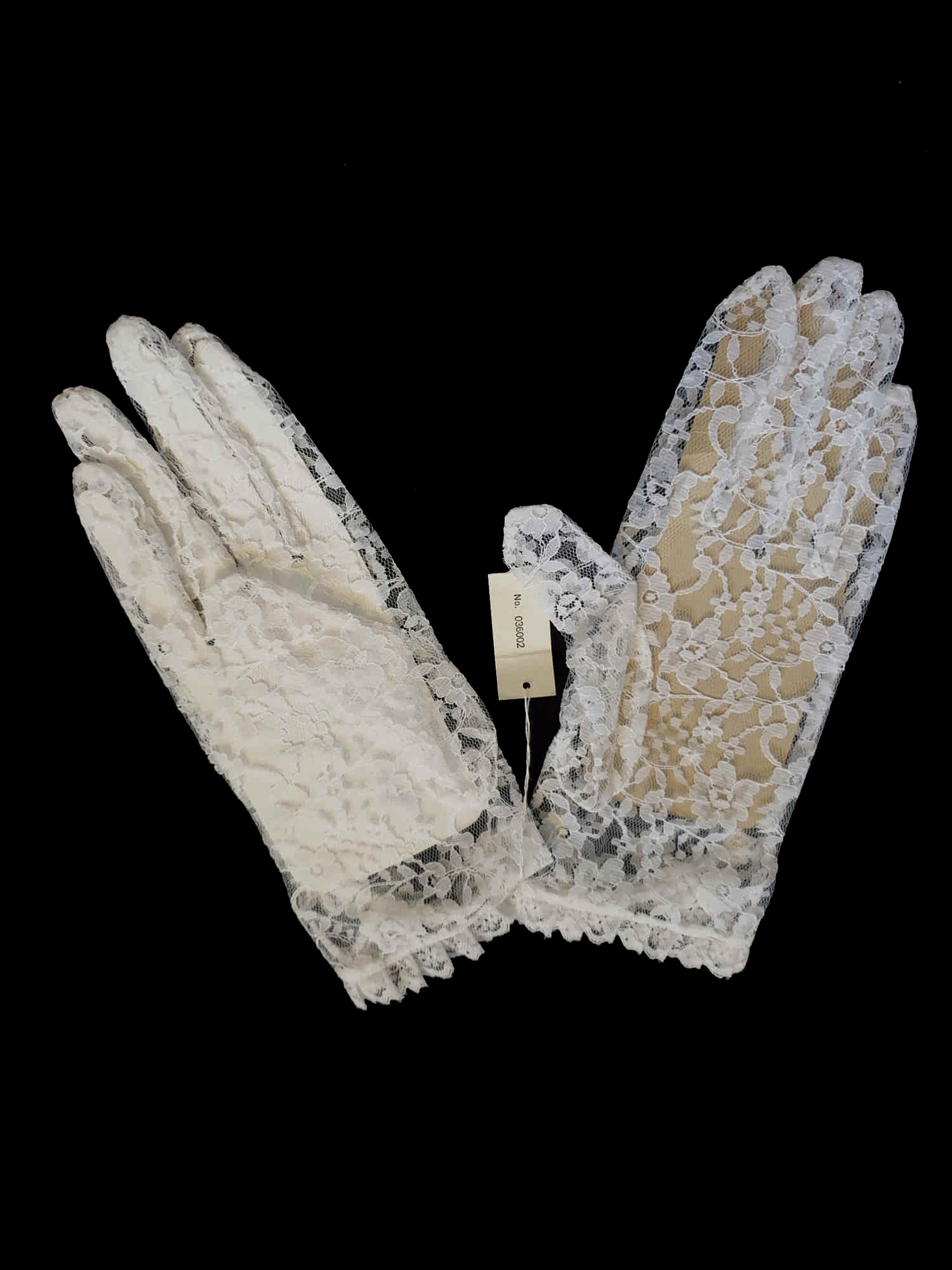 New old stock - beautiful lace bridal gloves with diamante trim, unsold stock from a former 1980s bridal boutique. White lace gloves are below-wrist length and have a shaped opening trimmed with more lace and a line of diamantes. 100% nylon. Made in Hong Kong for Jendi - 1980s.