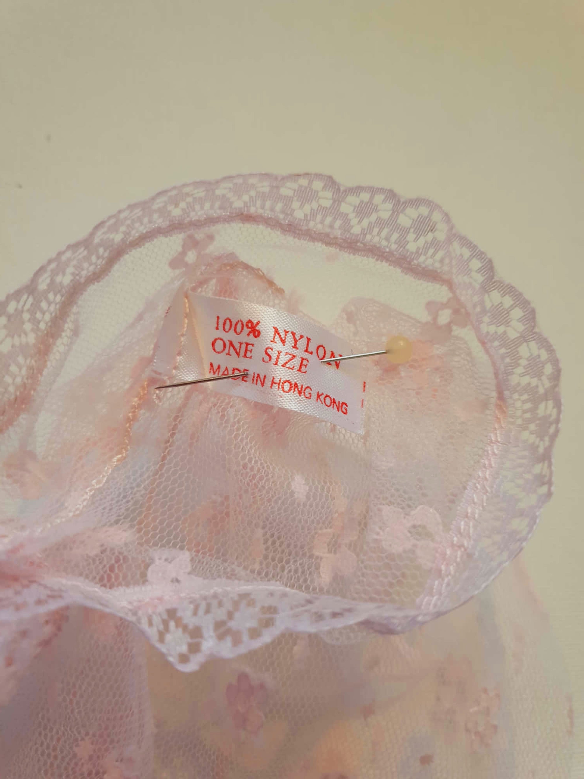 New old stock - Dainty lace mitts for a special occasion. Pale pink lace mitts or fingerless gloves are mid-forearm length. Trimmed with narrow lace at the edges. 100% nylon. Made in Hong Kong. No brand label. From a former 1980s bridal boutique. Mint condition - brand new and never used.