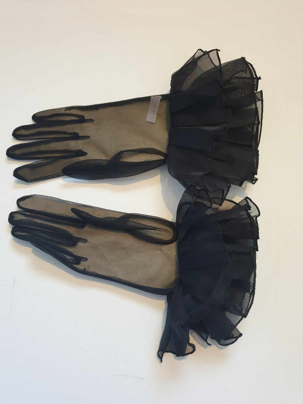 New Old Stock. Beautiful sheer black gloves have a very large double ruffle at the wrist. Elastic at the wrists. 100% nylon. Made in Hong Kong. Size 7.