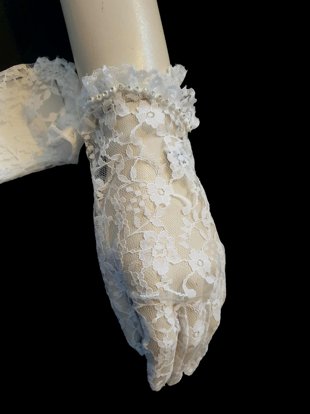 New old stock - beautiful lace bridal gloves with diamante trim, unsold stock from a former 1980s bridal boutique. White lace gloves are below-wrist length and have a shaped opening trimmed with more lace and a line of diamantes. 100% nylon. Made in Hong Kong for Jendi - 1980s.