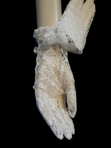 New old stock - beautiful lace bridal gloves with diamante trim, unsold stock from a former 1980s bridal boutique. White lace gloves are below-wrist length and have a shaped opening trimmed with more lace and a line of diamantes. 100% nylon. Made in Hong Kong for Jendi - 1980s.