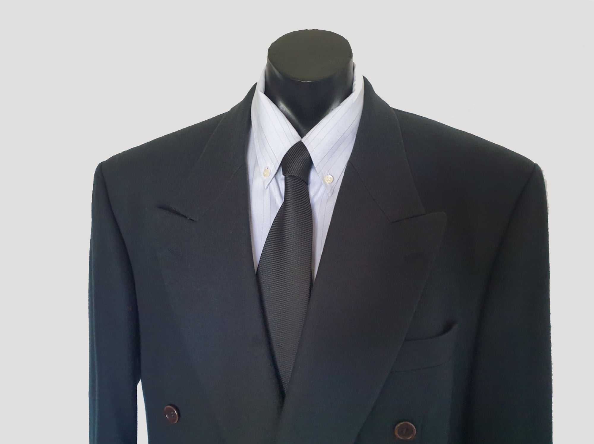 Very dark green (can appear black) double-breasted jacket has peak lapels and no rear vent. Six button front stance and three button sleeve trim. Two front flapped pockets, breast pocket and three interior pockets. Fully lined. Fabric is 70% wool, 20% nylon and 10% cashmere. 1990s, 42M