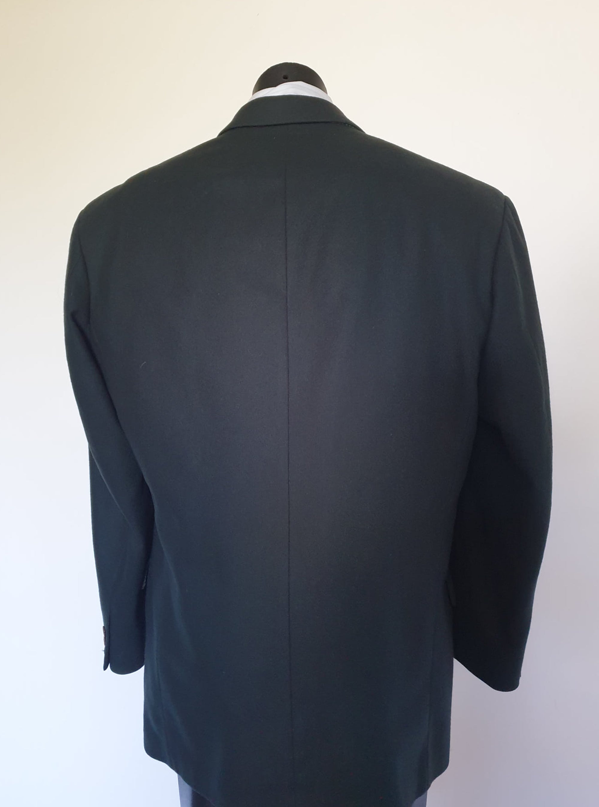 Very dark green (can appear black) double-breasted jacket has peak lapels and no rear vent. Six button front stance and three button sleeve trim. Two front flapped pockets, breast pocket and three interior pockets. Fully lined. Fabric is 70% wool, 20% nylon and 10% cashmere. 1990s, 42M