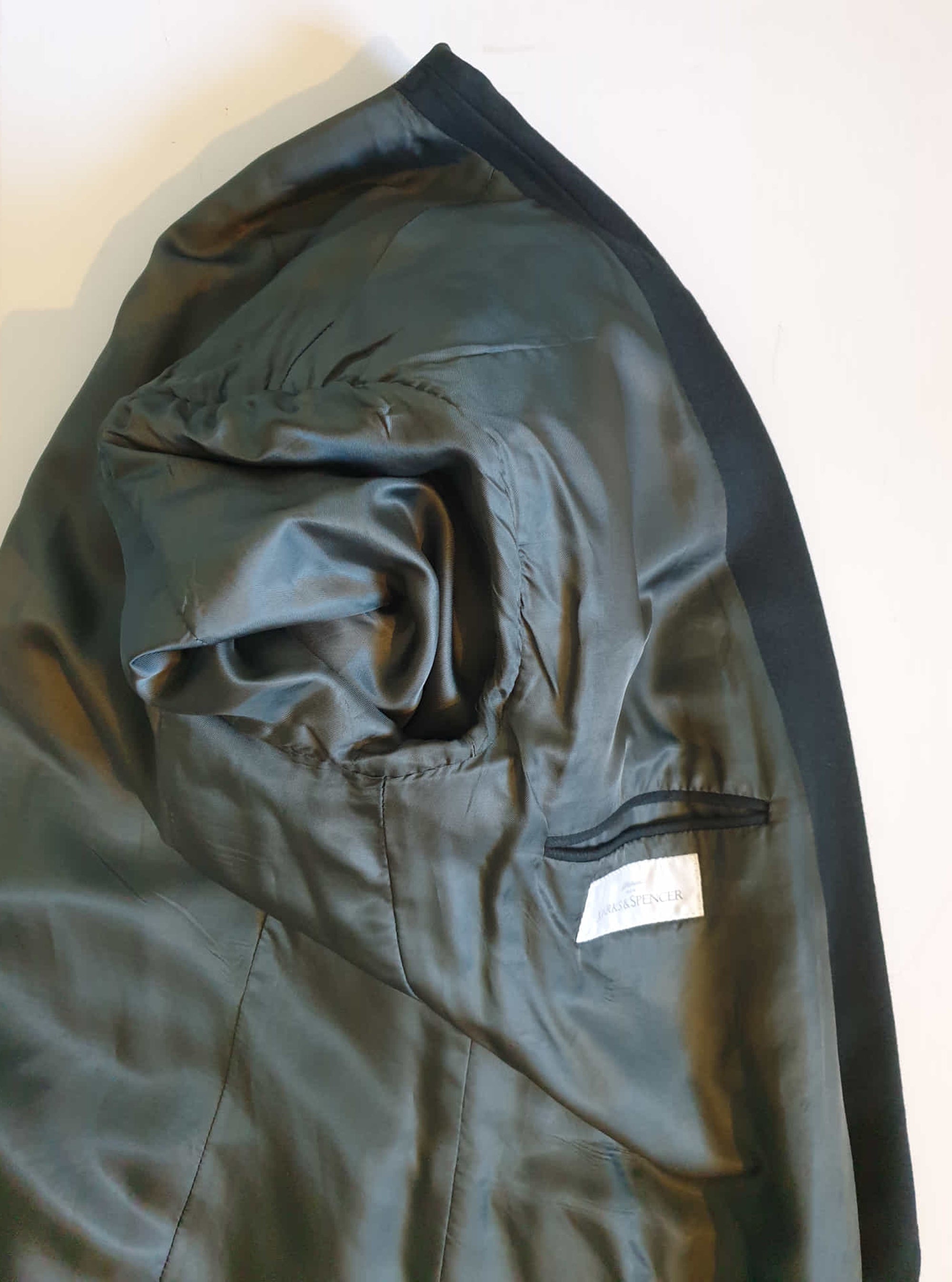 Very dark green (can appear black) double-breasted jacket has peak lapels and no rear vent. Six button front stance and three button sleeve trim. Two front flapped pockets, breast pocket and three interior pockets. Fully lined. Fabric is 70% wool, 20% nylon and 10% cashmere. 1990s, 42M