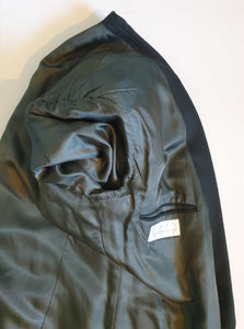 Very dark green (can appear black) double-breasted jacket has peak lapels and no rear vent. Six button front stance and three button sleeve trim. Two front flapped pockets, breast pocket and three interior pockets. Fully lined. Fabric is 70% wool, 20% nylon and 10% cashmere. 1990s, 42M