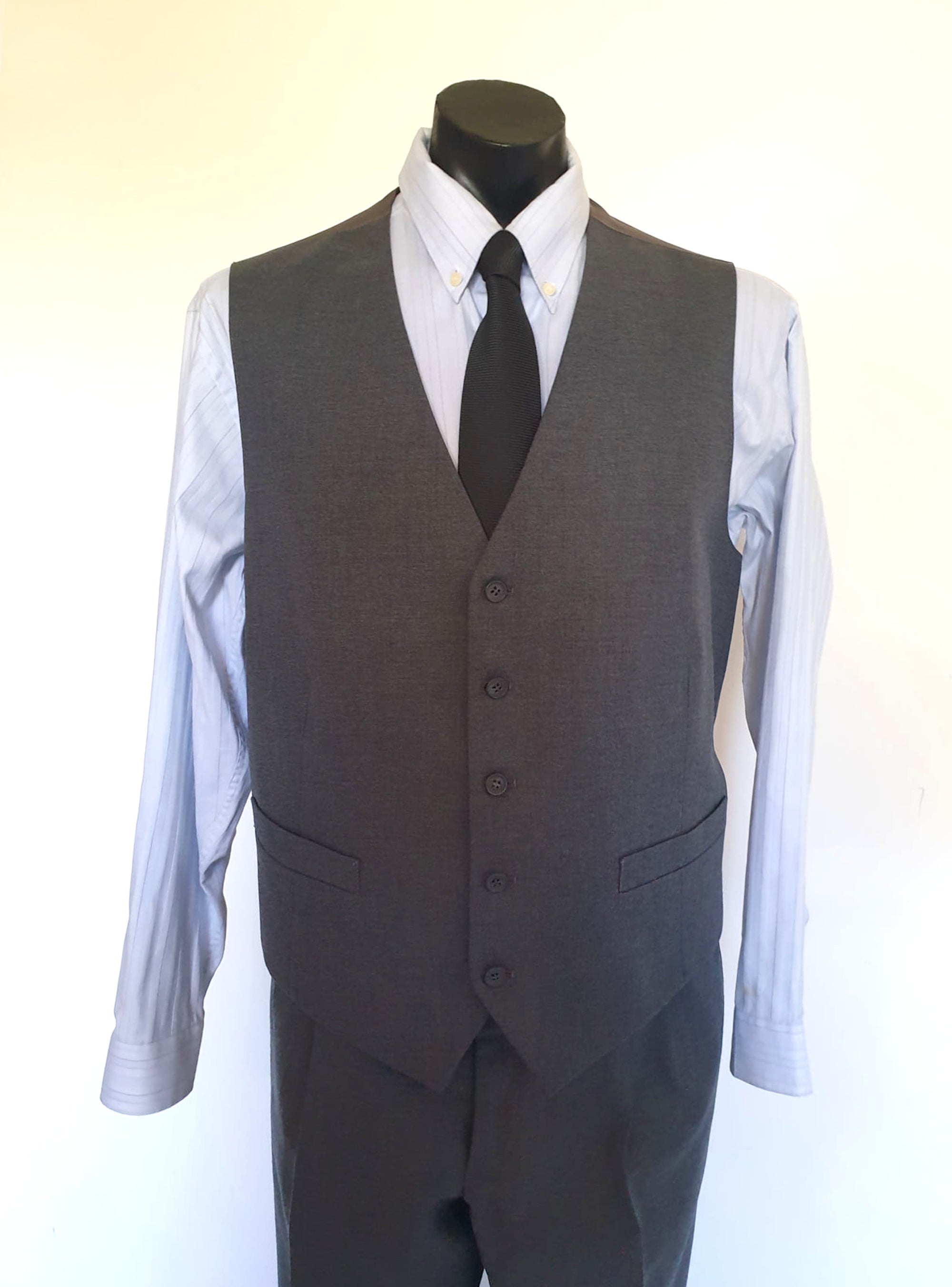 The suit jacket has notched lapels, flapped pockets, breast pocket, two button closure, three button sleeve trim and three interior pockets. It has two rear vents.
The vest has two pockets and five button closure. There is no belt for rear adjustment.
The trousers have straight legs, two front pleats at the waist, two diagonal side pockets, coin pocket and two buttoning rear pockets. 
The fabric is 80% wool, 20% polyester. Made by the iconic Fletcher Jones Australia. Conveniently dated 1-5-1990. Size 117R.