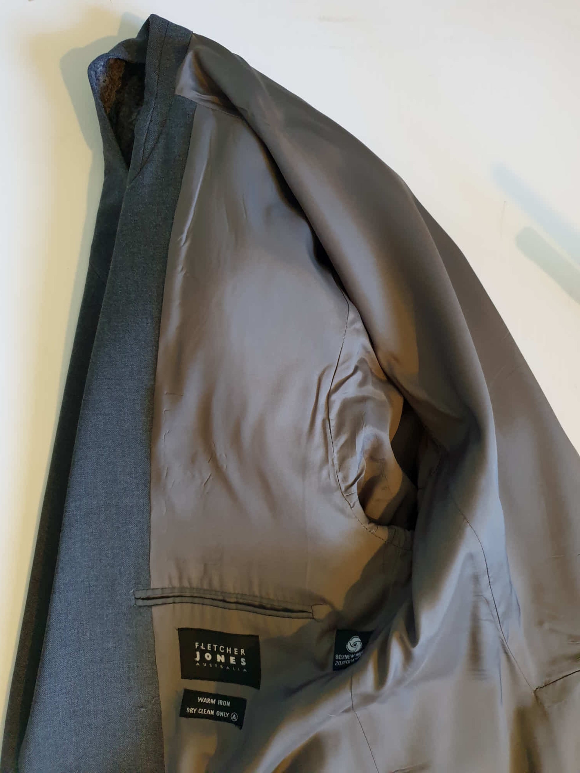 The suit jacket has notched lapels, flapped pockets, breast pocket, two button closure, three button sleeve trim and three interior pockets. It has two rear vents.
The vest has two pockets and five button closure. There is no belt for rear adjustment.
The trousers have straight legs, two front pleats at the waist, two diagonal side pockets, coin pocket and two buttoning rear pockets. 
The fabric is 80% wool, 20% polyester. Made by the iconic Fletcher Jones Australia. Conveniently dated 1-5-1990. Size 117R.