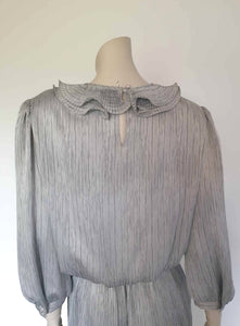 Beautiful and classy secretary style dress. Mid-calf length silver grey dress has three-quarter length buttoning sleeves and a circular ruffled collar. The skirt has very narrow permanent pleats to about knee level. The same pleated fabric has been used for the collar. The bodice is a full blouson look.  Brand is The Dress Company - 1980s. Medium