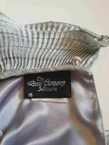 Beautiful and classy secretary style dress. Mid-calf length silver grey dress has three-quarter length buttoning sleeves and a circular ruffled collar. The skirt has very narrow permanent pleats to about knee level. The same pleated fabric has been used for the collar. The bodice is a full blouson look.  Brand is The Dress Company - 1980s. Medium