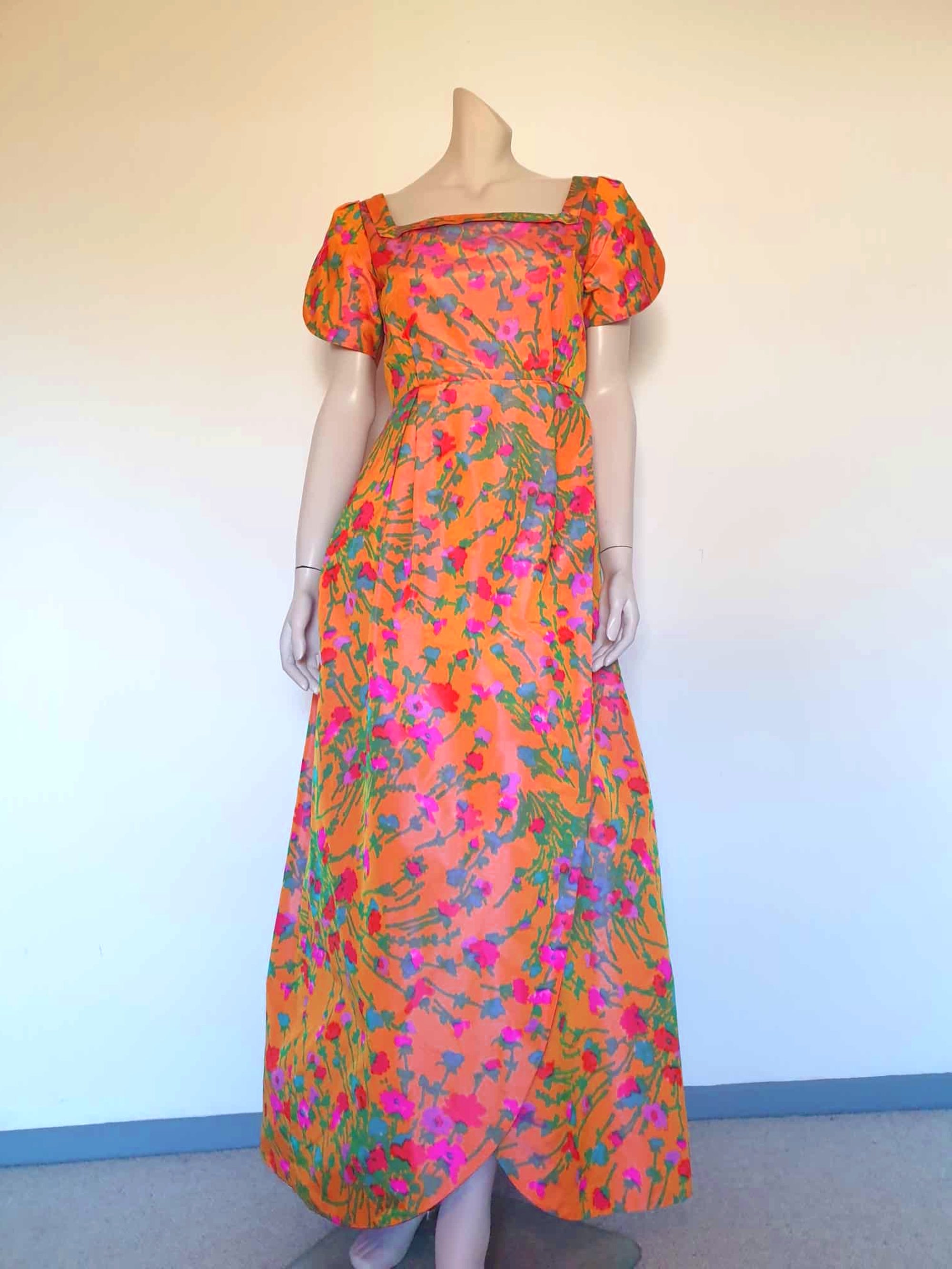 Superbly made gown in bright orange and pink florals in a very swishy parachute type fabric. 1950s style dress has wrap over sleeves exposing the vivid orange red lining. Square neckline. The skirt is wrapped at the front and pleated into the waist. It's very full at the back. Closes at the back with a nylon zip. The fabric is shot so that it can appear pink from different angles. The gown looks to have been made by a professional dressmaker  probably late 20th century. Medium