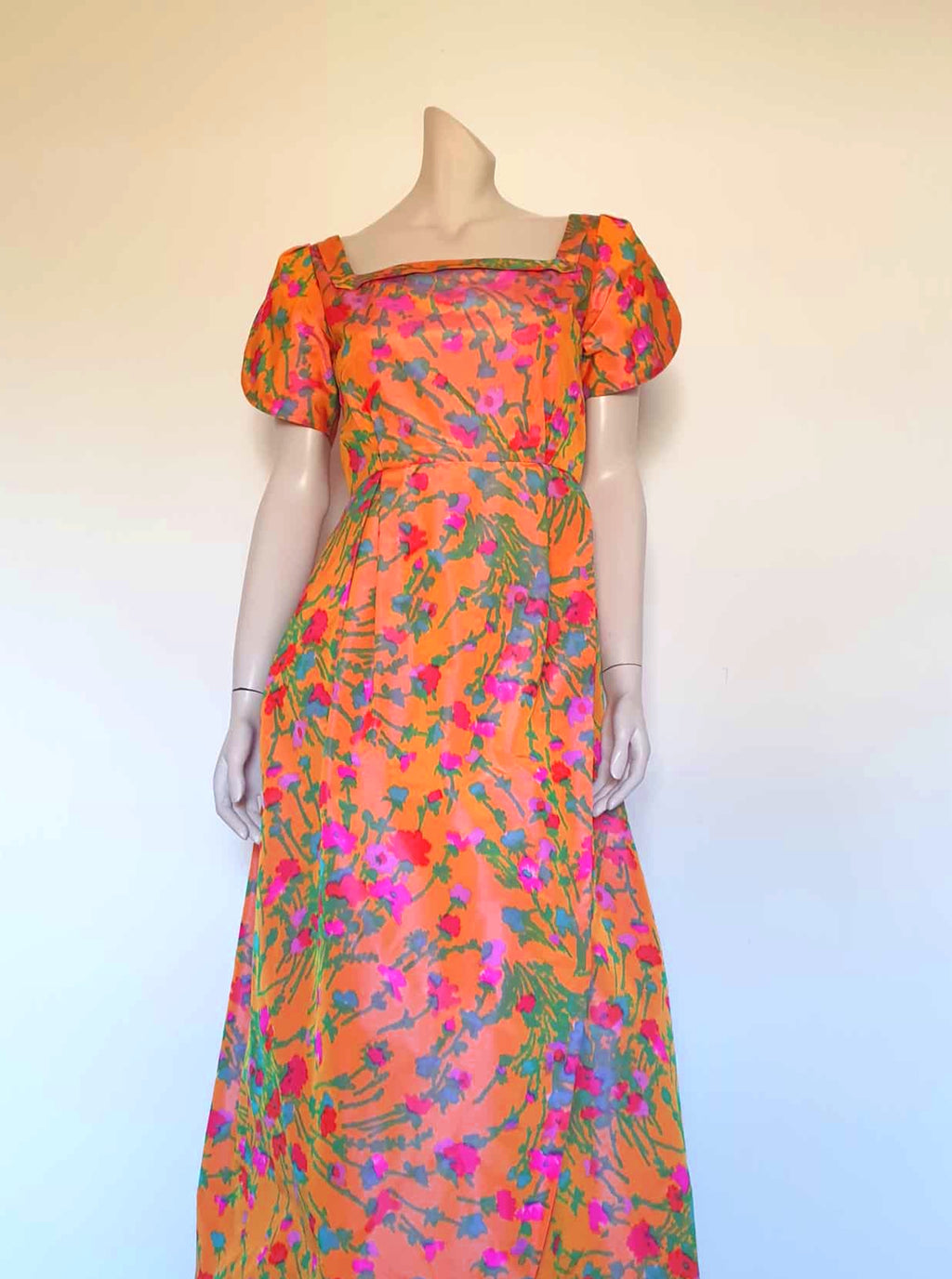 Superbly made gown in bright orange and pink florals in a very swishy parachute type fabric. 1950s style dress has wrap over sleeves exposing the vivid orange red lining. Square neckline. The skirt is wrapped at the front and pleated into the waist. It's very full at the back. Closes at the back with a nylon zip. The fabric is shot so that it can appear pink from different angles. The gown looks to have been made by a professional dressmaker  probably late 20th century. Medium