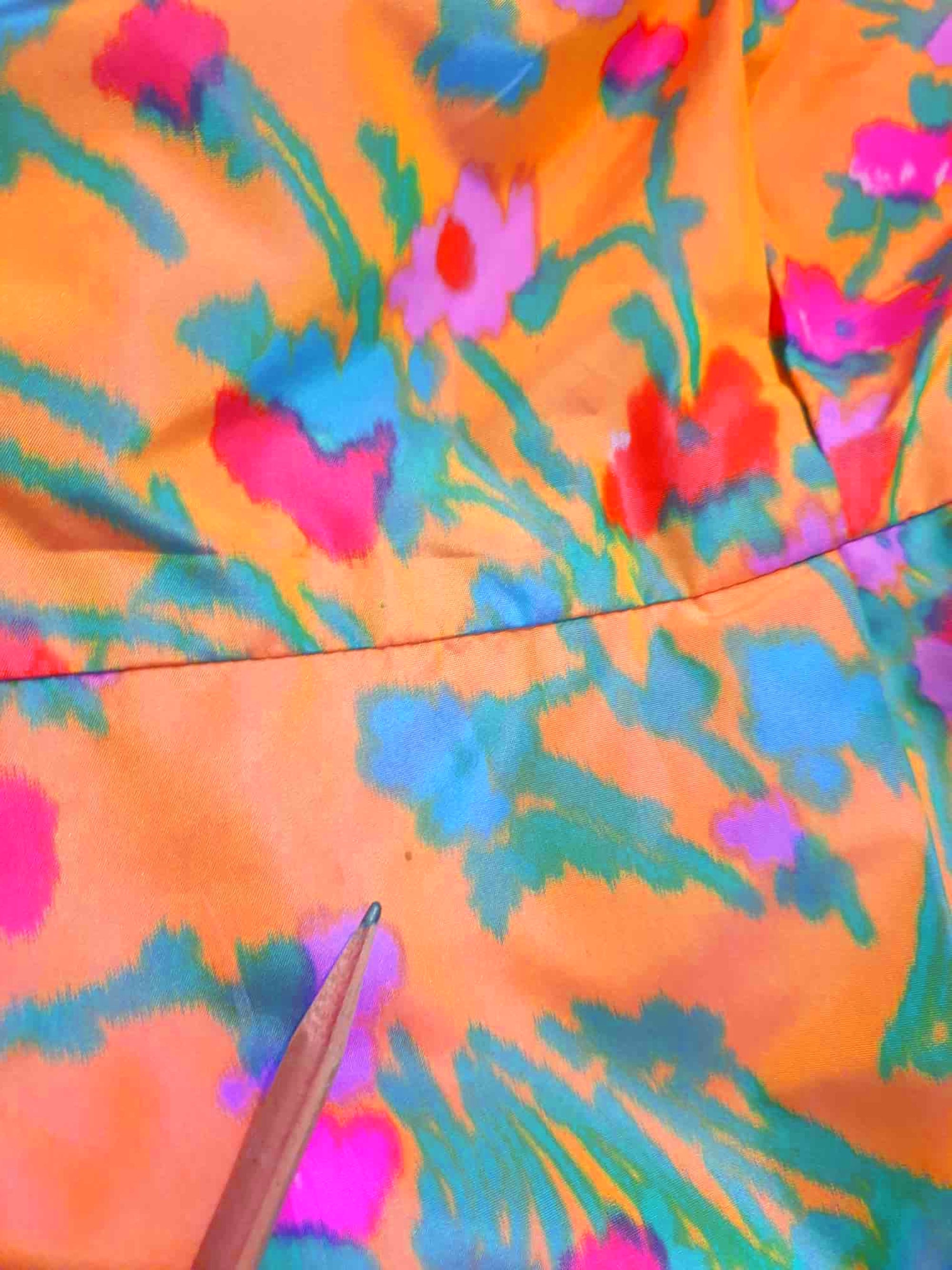 Superbly made gown in bright orange and pink florals in a very swishy parachute type fabric. 1950s style dress has wrap over sleeves exposing the vivid orange red lining. Square neckline. The skirt is wrapped at the front and pleated into the waist. It's very full at the back. Closes at the back with a nylon zip. The fabric is shot so that it can appear pink from different angles. The gown looks to have been made by a professional dressmaker  probably late 20th century. Medium