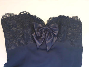 Classy strapless formal dress with optional chiffon scarf. Navy blue strapless gown has a lace bodice with boning and is trimmed with a large satin bow at the bust. The long flared skirt is chiffon over a silky lining. Closes with a zip in the back. Fabric is 100% polyester. Made in Australia for Aurelie - 1980s. Extra Small.