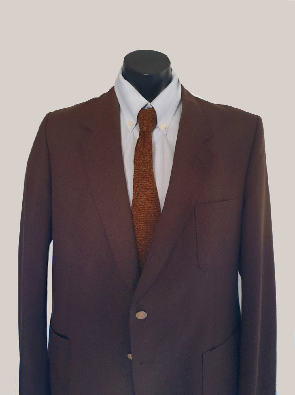 1970s blazer is chocolate brown and has notched lapels. It sports pewter coloured metal buttons featuring a heraldic crest. Three patch pockets at the front, one has a coin pocket. Three interior pockets. One button sleeve trim and two button closure. Rear vent. Fabric is 55% polyester, 45% wool. Lining appears to be rayon. Brand is the well known Australian tailoring company Stafford Ellinson - 1970s. 46RXL