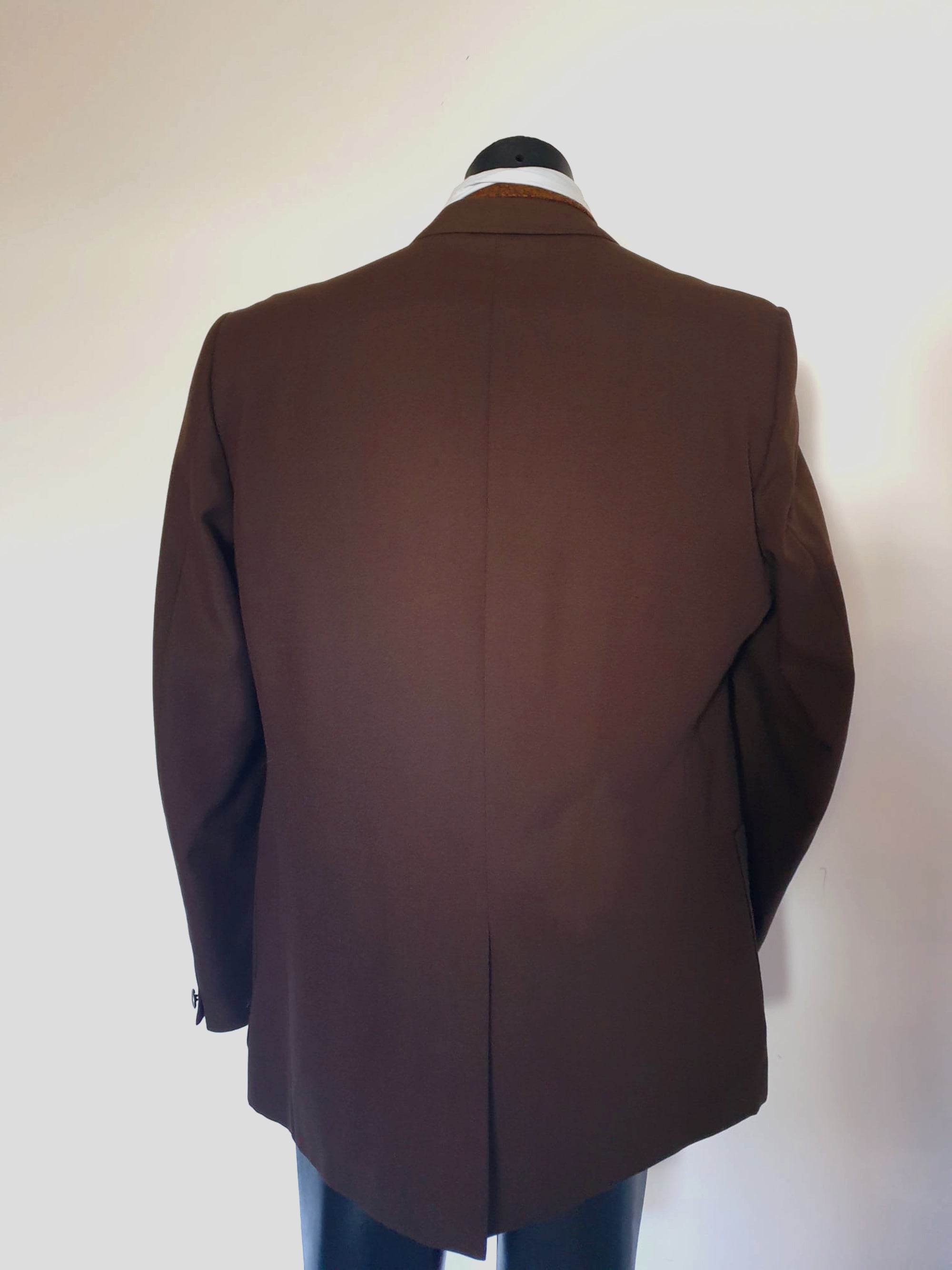 1970s blazer is chocolate brown and has notched lapels. It sports pewter coloured metal buttons featuring a heraldic crest. Three patch pockets at the front, one has a coin pocket. Three interior pockets. One button sleeve trim and two button closure. Rear vent. Fabric is 55% polyester, 45% wool. Lining appears to be rayon. Brand is the well known Australian tailoring company Stafford Ellinson - 1970s. 46RXL