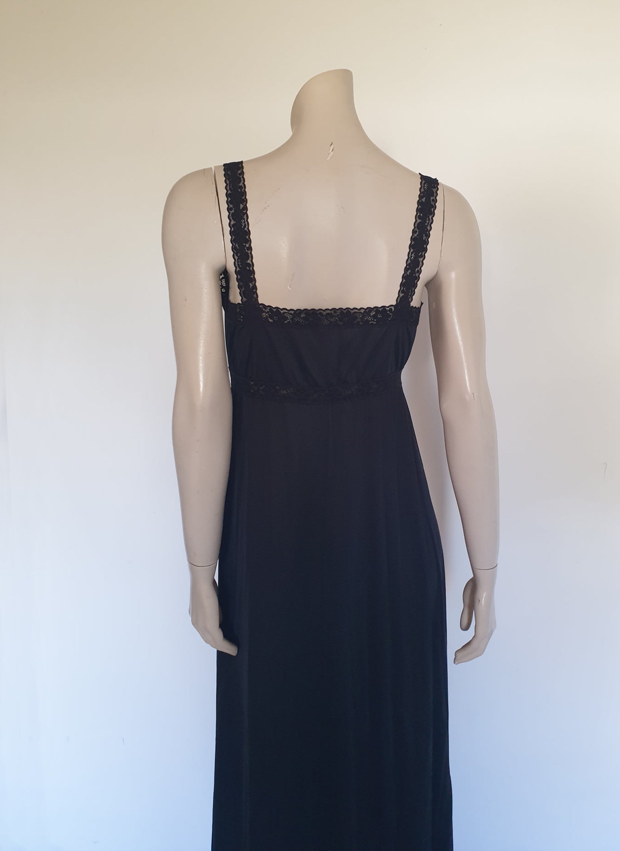 Black maxi slip originally worn under an evening gown or funky maxi dress. You can use it as a slip, nightgown or dress. It has stretch lace straps and bodice trim. Straps are no adjustable. Fabric is "no cling" nylon. Brand is Osti - 1970s. Medium