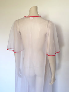 Super cute sheer white robe has red apples appliqued over the bust. The robe has full, elbow-length flutter sleeves and all edges are bound with red extending into ties at the neck and bust.   Ankle length. Fabric is polyamide (nylon). Made in Argentina. No brand label - 1970s. Medium