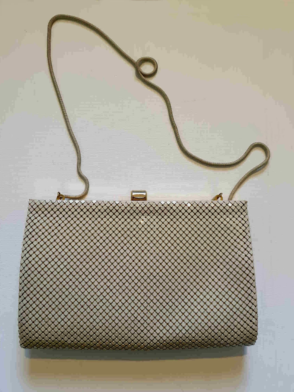 Beige mesh purse can either be used as a shoulder bag or as a clutch. Gold frame and kiss clasp and beige rat tail chain. The interior is brown satin, and has one zipped compartment and a pocket. The chain folds into the bag for use as a clutch. Brand is GC, also known as Goldcrest. 1970s-1980s.