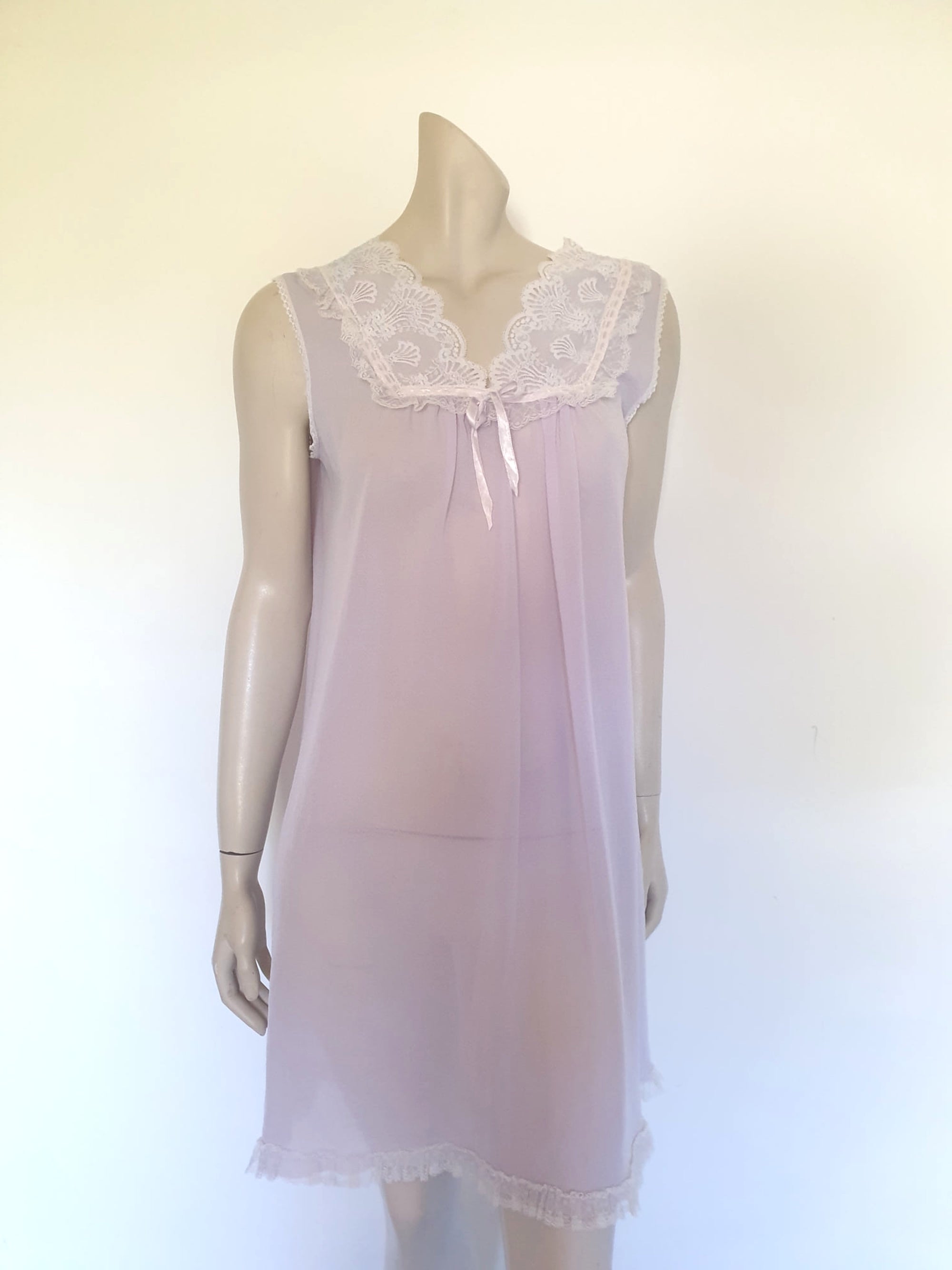 Pretty pale mauve crepe nightgown and robe set has a lace yoke tying at the neck with a ribbon on both the gown and robe. Pleas note: the colour is lighter than it appears in the photos. Above-knee length set has a high V neck and lace and pink ribbon trim at the yoke and sleeves. Hemline is also lace trimmed.  The robe has short sleeves, the gown is sleeveless. Fabric is nylon crepe. Brand is Irene - 1970s. Medium.