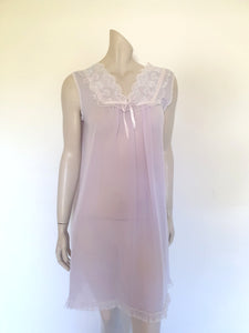 Pretty pale mauve crepe nightgown and robe set has a lace yoke tying at the neck with a ribbon on both the gown and robe. Pleas note: the colour is lighter than it appears in the photos. Above-knee length set has a high V neck and lace and pink ribbon trim at the yoke and sleeves. Hemline is also lace trimmed.  The robe has short sleeves, the gown is sleeveless. Fabric is nylon crepe. Brand is Irene - 1970s. Medium.