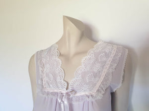 Pretty pale mauve crepe nightgown and robe set has a lace yoke tying at the neck with a ribbon on both the gown and robe. Pleas note: the colour is lighter than it appears in the photos. Above-knee length set has a high V neck and lace and pink ribbon trim at the yoke and sleeves. Hemline is also lace trimmed.  The robe has short sleeves, the gown is sleeveless. Fabric is nylon crepe. Brand is Irene - 1970s. Medium.