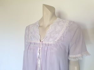 Pretty pale mauve crepe nightgown and robe set has a lace yoke tying at the neck with a ribbon on both the gown and robe. Pleas note: the colour is lighter than it appears in the photos. Above-knee length set has a high V neck and lace and pink ribbon trim at the yoke and sleeves. Hemline is also lace trimmed.  The robe has short sleeves, the gown is sleeveless. Fabric is nylon crepe. Brand is Irene - 1970s. Medium.