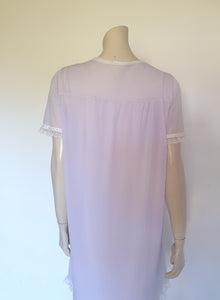 Pretty pale mauve crepe nightgown and robe set has a lace yoke tying at the neck with a ribbon on both the gown and robe. Pleas note: the colour is lighter than it appears in the photos. Above-knee length set has a high V neck and lace and pink ribbon trim at the yoke and sleeves. Hemline is also lace trimmed.  The robe has short sleeves, the gown is sleeveless. Fabric is nylon crepe. Brand is Irene - 1970s. Medium.