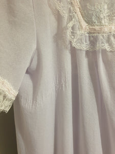 Pretty pale mauve crepe nightgown and robe set has a lace yoke tying at the neck with a ribbon on both the gown and robe. Pleas note: the colour is lighter than it appears in the photos. Above-knee length set has a high V neck and lace and pink ribbon trim at the yoke and sleeves. Hemline is also lace trimmed.  The robe has short sleeves, the gown is sleeveless. Fabric is nylon crepe. Brand is Irene - 1970s. Medium.
