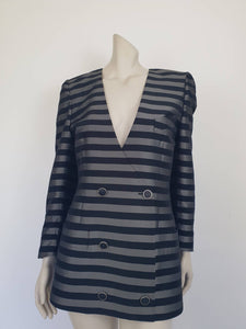 Grey and black striped longline jacket by Australian designer Teena Varigos. 
This V-necked jacket is truly double-breasted and can be worn buttoned either left over right or right over left. It's below hip length. It has two functional front pockets and a breast pocket. Shoulders are emphasised in true '80s style. The sleeves taper to the wrist. Two button sleeve trim and six button front stance. Fabric has the look of silk but is actually polyester - no fabric labels. Teena Varigos - 1980s.