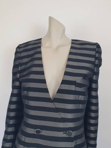 Grey and black striped longline jacket by Australian designer Teena Varigos. 
This V-necked jacket is truly double-breasted and can be worn buttoned either left over right or right over left. It's below hip length. It has two functional front pockets and a breast pocket. Shoulders are emphasised in true '80s style. The sleeves taper to the wrist. Two button sleeve trim and six button front stance. Fabric has the look of silk but is actually polyester - no fabric labels. Teena Varigos - 1980s.