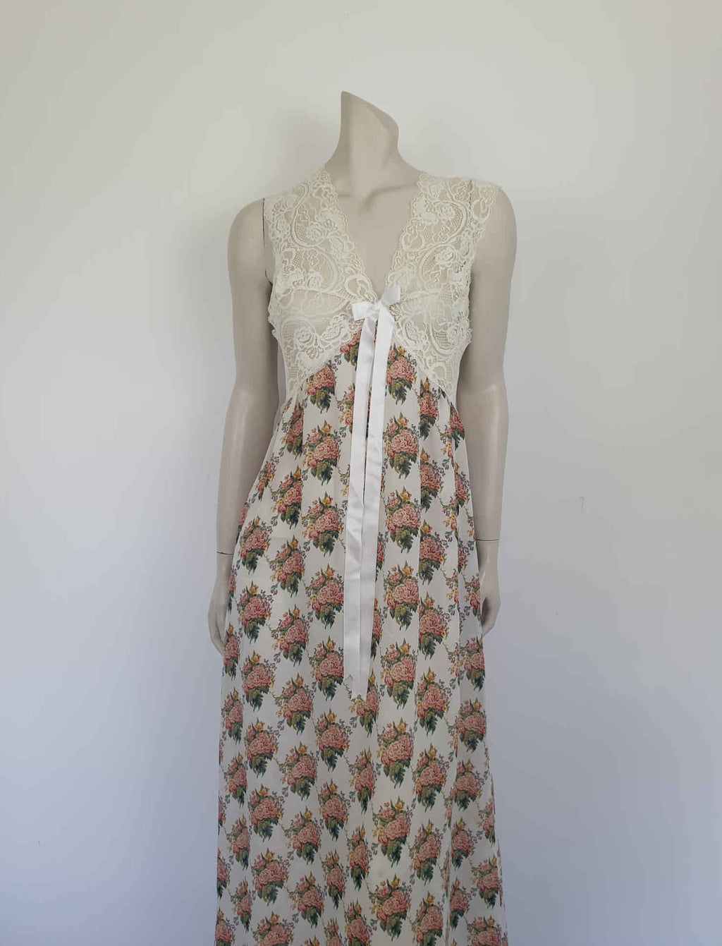 Beautiful and elegant nightgown. Long nightgown has a pink and green floral print on a cream ground. The fitted front bodice is cream stretch lace. There's also panel of lace at centre back. Trimmed with a satin bow and long ribbons beneath the bust. There are no labels, but the fabric is polyester georgette. 1980s. Bust 92 cm (36")