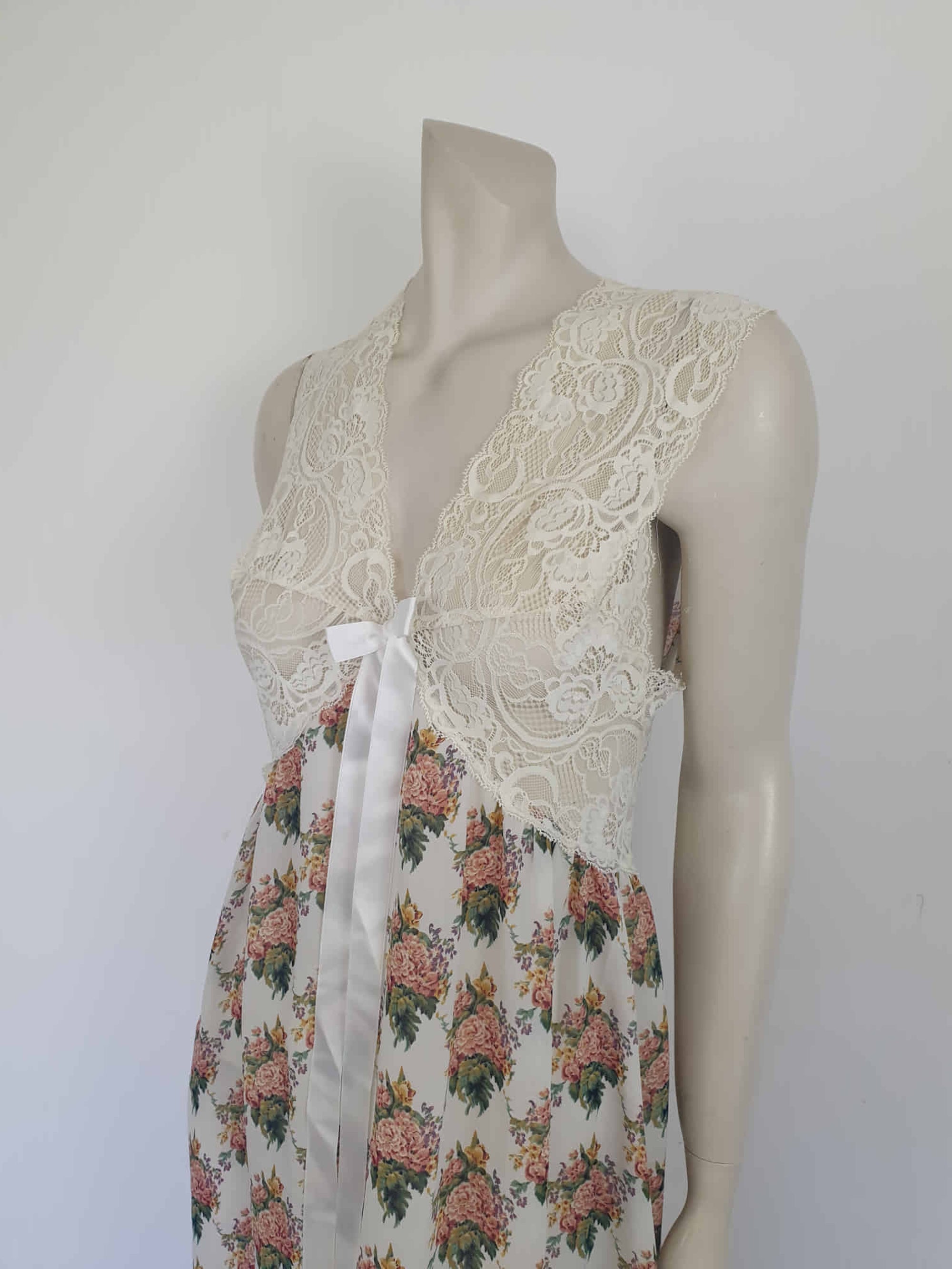Beautiful and elegant nightgown. Long nightgown has a pink and green floral print on a cream ground. The fitted front bodice is cream stretch lace. There's also panel of lace at centre back. Trimmed with a satin bow and long ribbons beneath the bust. There are no labels, but the fabric is polyester georgette. 1980s. Bust 92 cm (36")