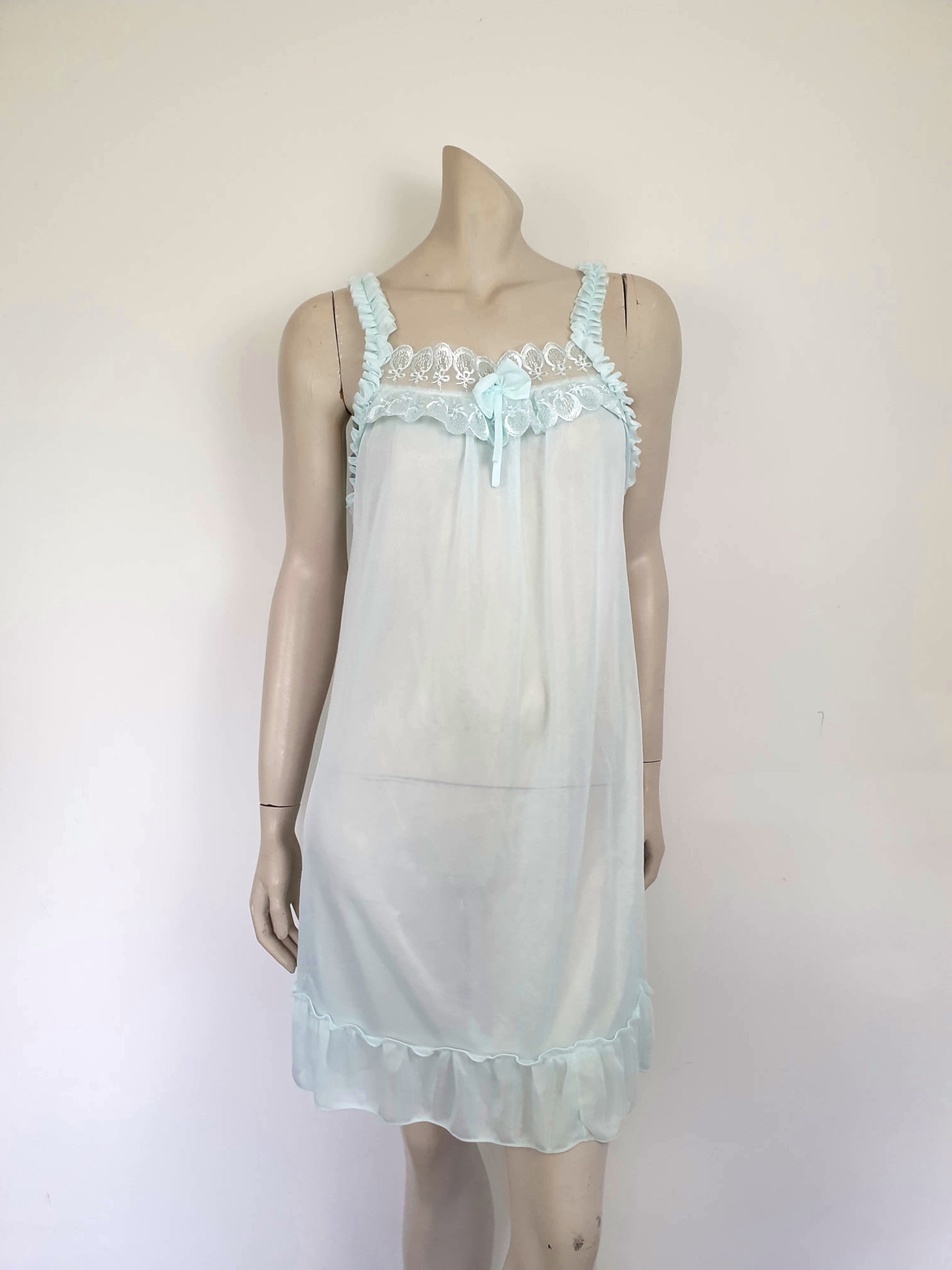 Pretty above knee length blue nightgown has ruffled straps and armholes, lace bodice and front bow. Ruffle at the hemline. Fabric is nylon. No brand label. Made in China. 1980s-1990s.