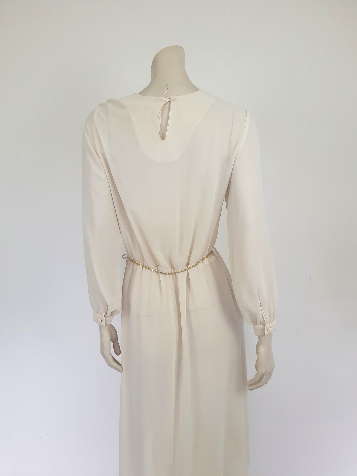 The perfect dress for Halloween, or for those who love spiders and spooky all year round. Pale beige (almost cream) crepe dress with an amazing yoke embroidered with a spiderweb, complete with gold spider. Dress is below-knee length, and has long sleeves which button at the cuffs. It just pulls on over the head and has one button and loop closure at the back neck. There is a separate gold tinsel tie for the waist which runs through carriers. Fabric is polyester. Brand is Ojay - 1970s. Medium.