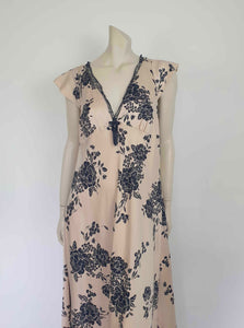 Long beige satin nightgown with large black floral print and flared capped sleeves. The skirt falls from beneath the bust. Slit to the thigh on one side. The V neck is trimmed with narrow black lace and a bow. Elasticised across the back. Fabric is polyester satin. Brand is illegible. 1990s-Y2K?