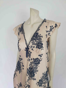 Long beige satin nightgown with large black floral print and flared capped sleeves. The skirt falls from beneath the bust. Slit to the thigh on one side. The V neck is trimmed with narrow black lace and a bow. Elasticised across the back. Fabric is polyester satin. Brand is illegible. 1990s-Y2K?