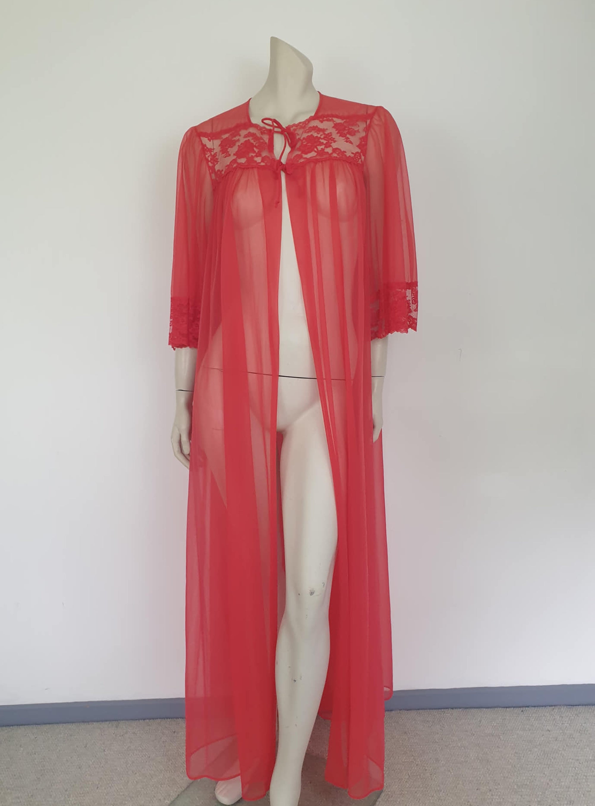 Glamourous  robe or peignoir is very sheer and has full three-quarter length sleeves trimmed with wide lace. The same lace is inserted across the front as a yoke. Closes with a double tie at the neck. Fabric is nylon. Made in the USA for Sears - 1960s. Medium