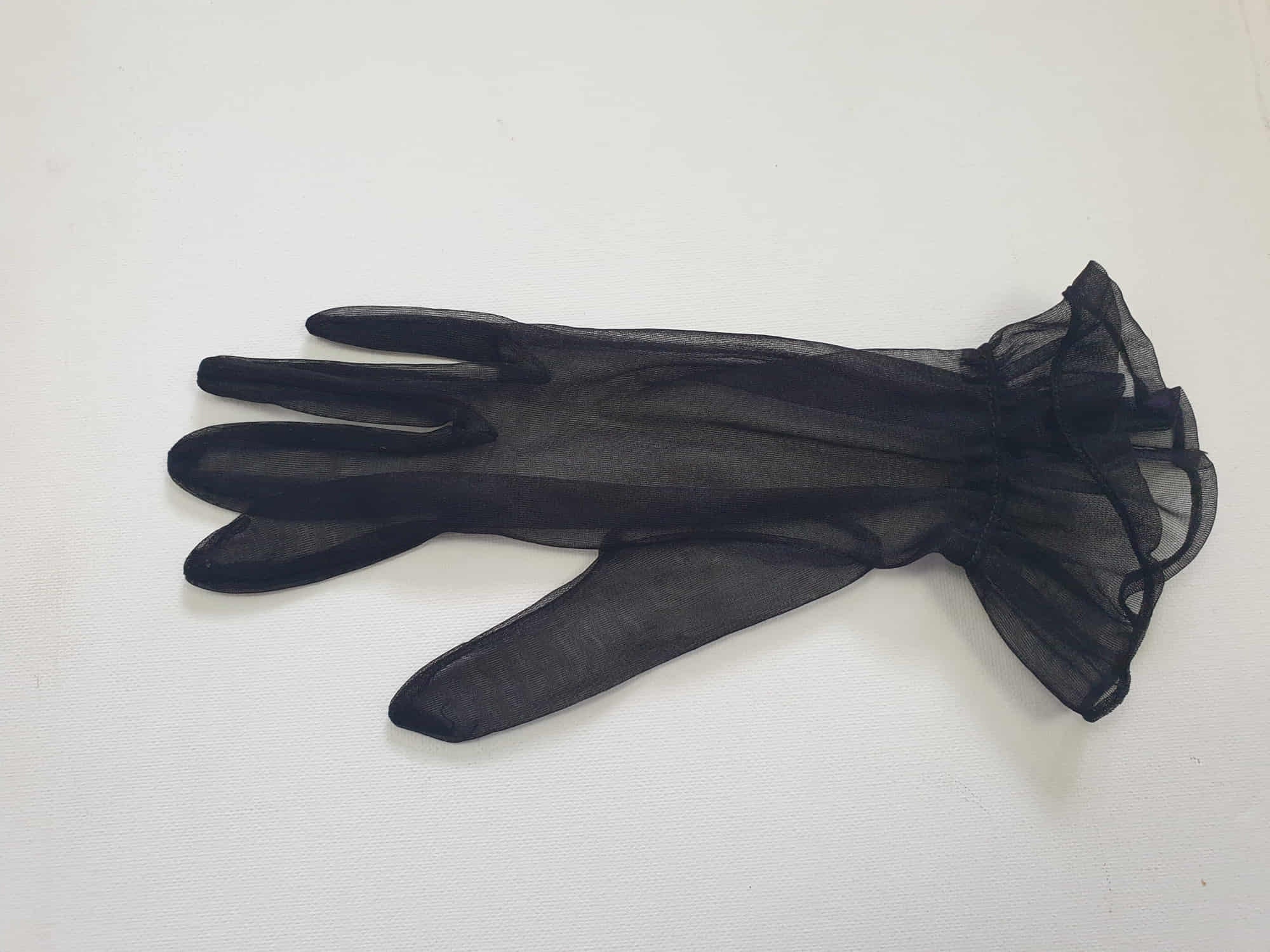New old stock - classy and sophisticated sheer black gloves with a ruffle at the wrist. Fabric is nylon. No tags. Medium.