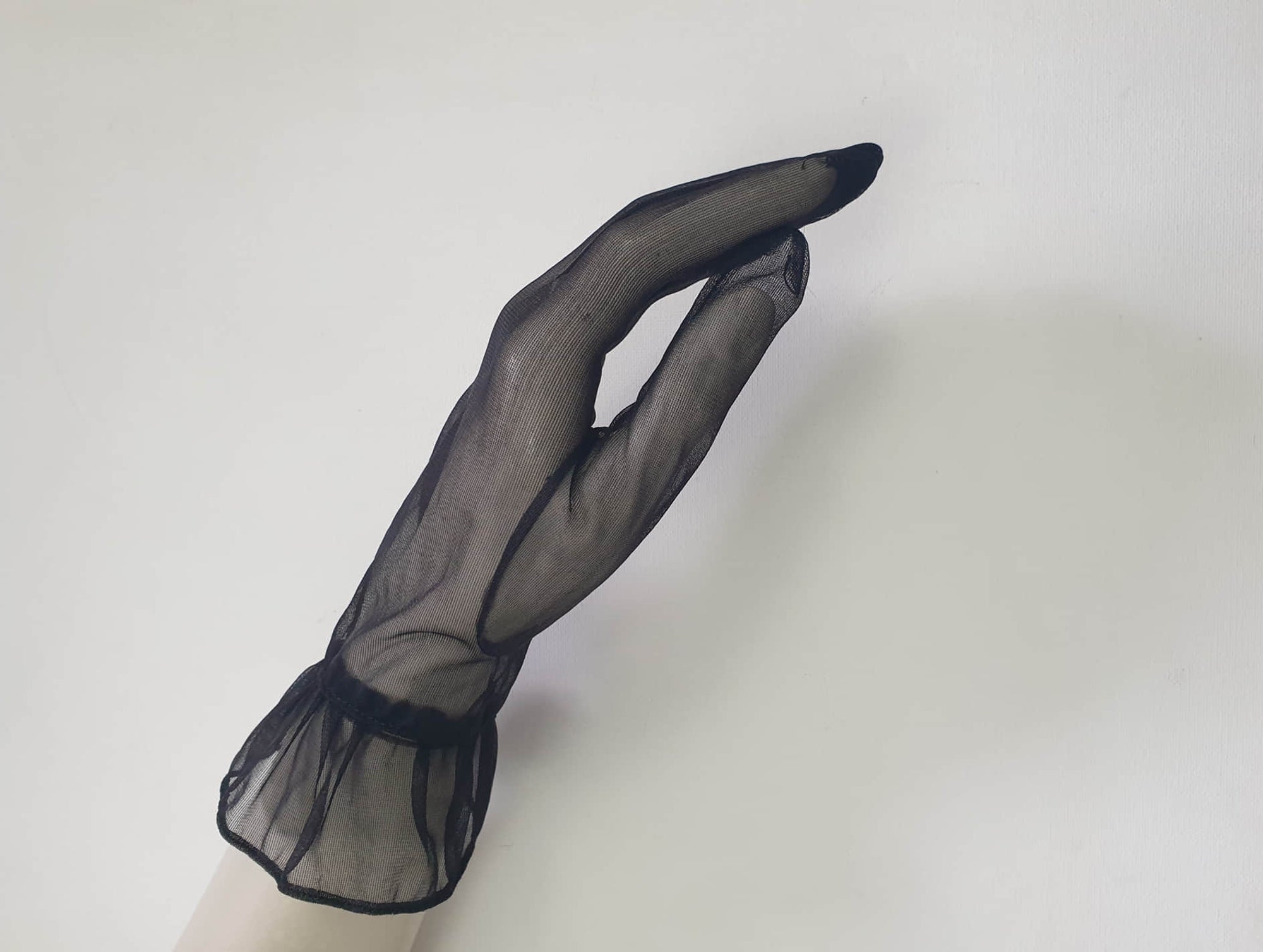 New old stock - classy and sophisticated sheer black gloves with a ruffle at the wrist. Fabric is nylon. No tags. Medium.