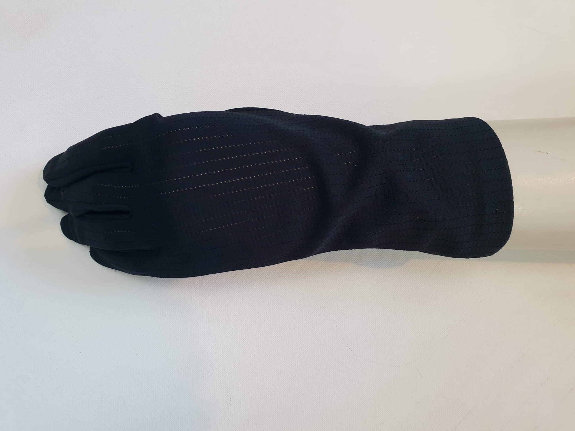 Smart black gloves for a classic dressed up look. Below wrist length stretch gloves have a striped pattern in the weave with a tiny transparent line, giving the look of a line of fine scoring. Mid weight. Fabric is nylon. No brand tag - 1960s. Large.