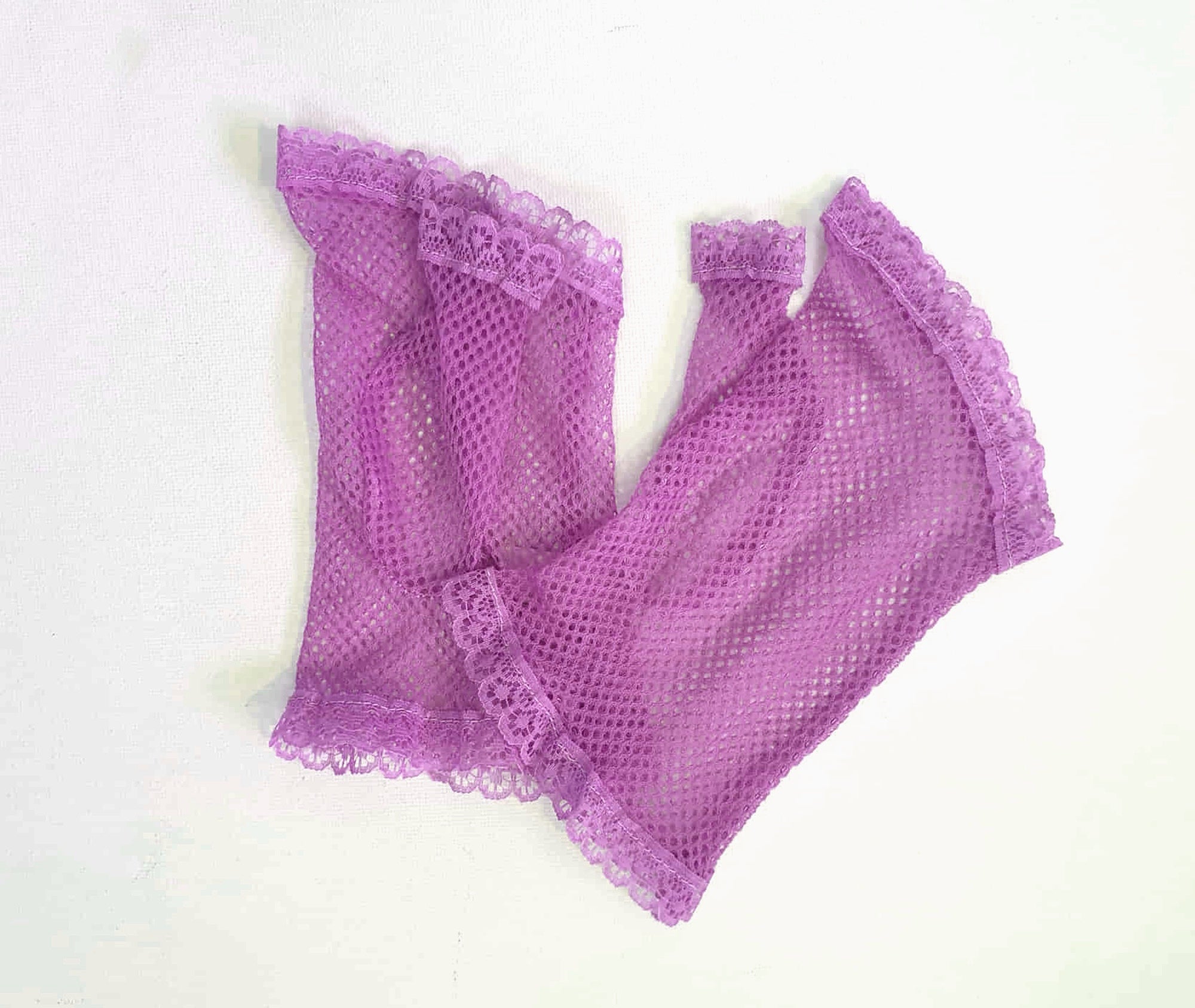 New old stock vintage purple fingerless gloves or mitts. Mitts are wrist length and are finished at all edges with lace trim. Colour is light purple - mauve - lavender. Fabric is nylon mesh. Made in Hong Kong. Unsold stock from a former 1980s bridal boutique. Small to Medium