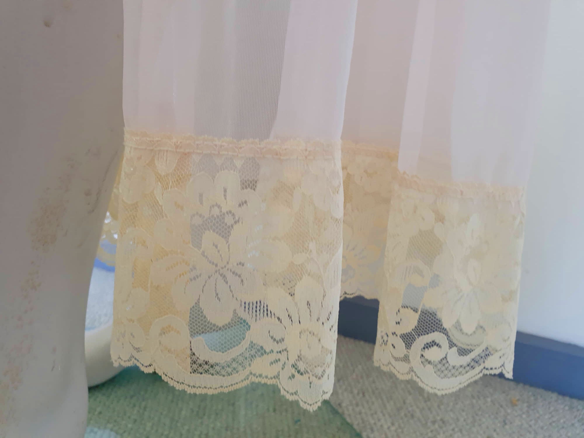 Sheer peach peignoir or long robe has puff sleeves trimmed with wide lace. The hem is also trimmed with wide ecru (beige) lace. The robe is gathered into the neckline, which is bound with satin and extends into a tie at the front. Fabric is a single layer of sheerest nylon. The tag is illegible - 1960s. Large.