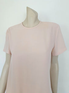 Above-knee length pale pink skirt and top set. Boxy top has short sleeves and is a pullover style, with a short opening buttoning at the back of the neck. There are removable shoulder pads. The straight skirt has a rear vent, rear zip and button fastening and is lined. Fabric is polyester crepe. Made in New Zealand for Suzanne Gregory - 1980s. Medium to Large.