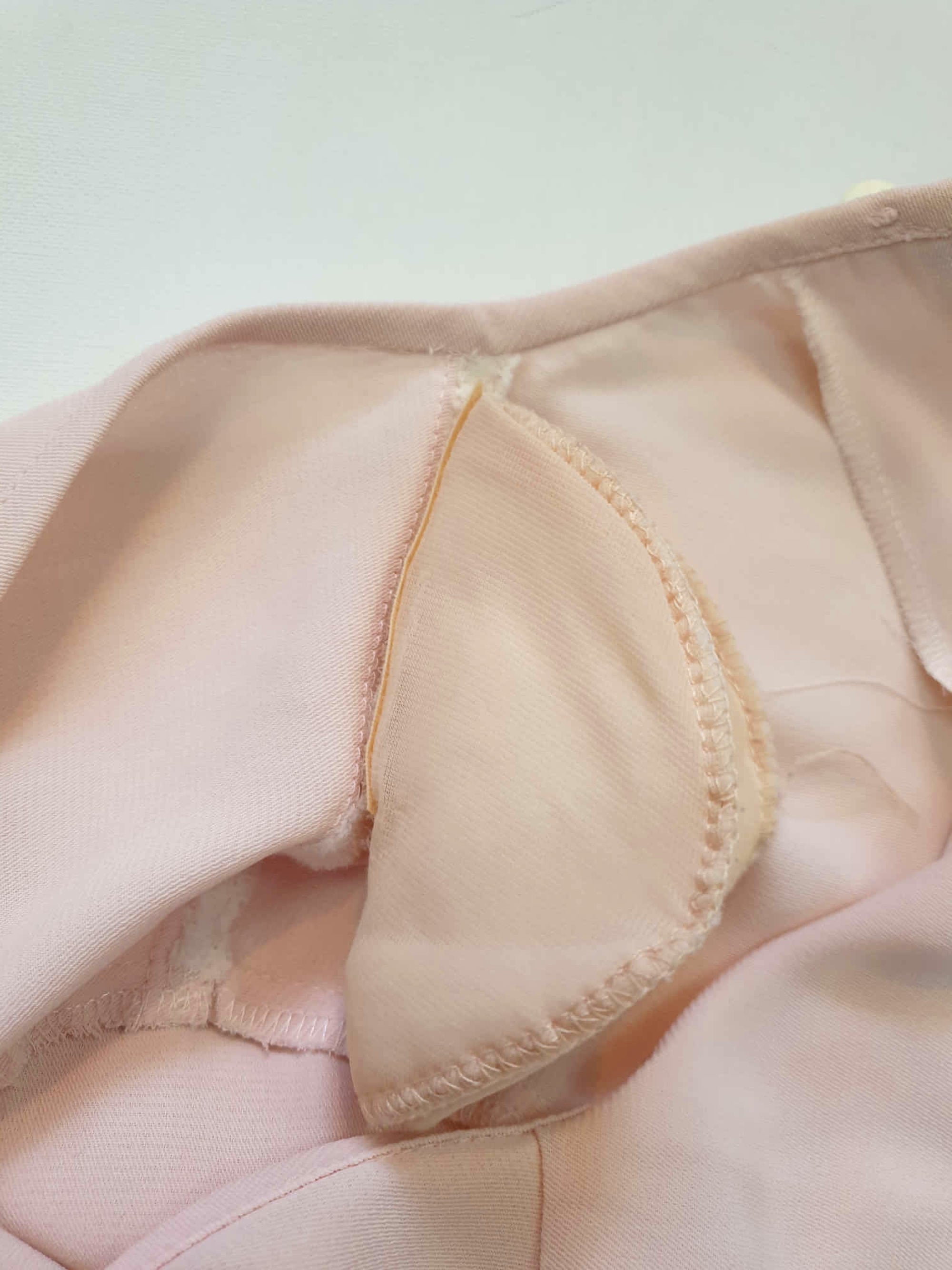 Above-knee length pale pink skirt and top set. Boxy top has short sleeves and is a pullover style, with a short opening buttoning at the back of the neck. There are removable shoulder pads. The straight skirt has a rear vent, rear zip and button fastening and is lined. Fabric is polyester crepe. Made in New Zealand for Suzanne Gregory - 1980s. Medium to Large.