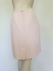 Above-knee length pale pink skirt and top set. Boxy top has short sleeves and is a pullover style, with a short opening buttoning at the back of the neck. There are removable shoulder pads. The straight skirt has a rear vent, rear zip and button fastening and is lined. Fabric is polyester crepe. Made in New Zealand for Suzanne Gregory - 1980s. Medium to Large.